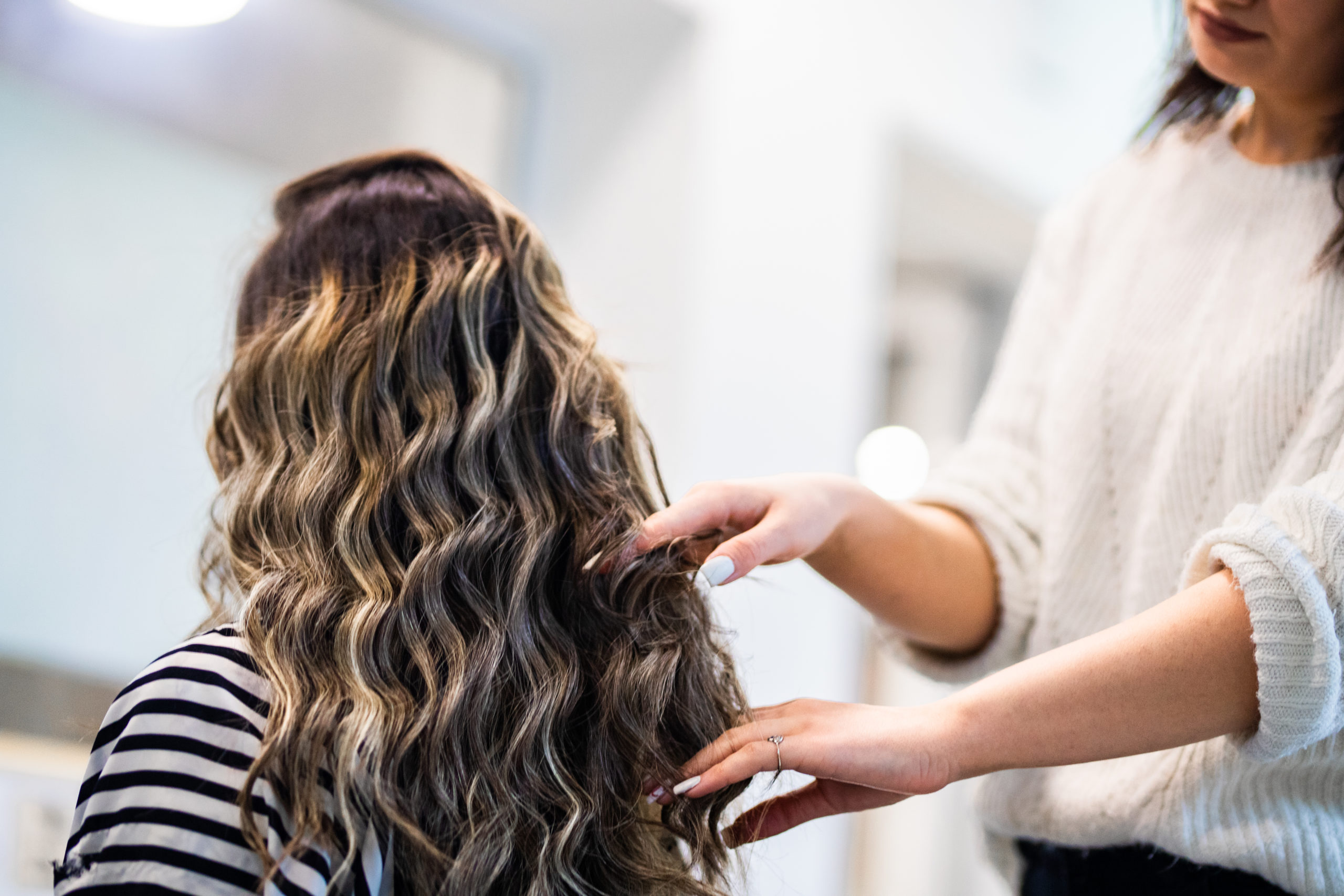 Women with beautiful long black hair at treatment in hairstylist salon