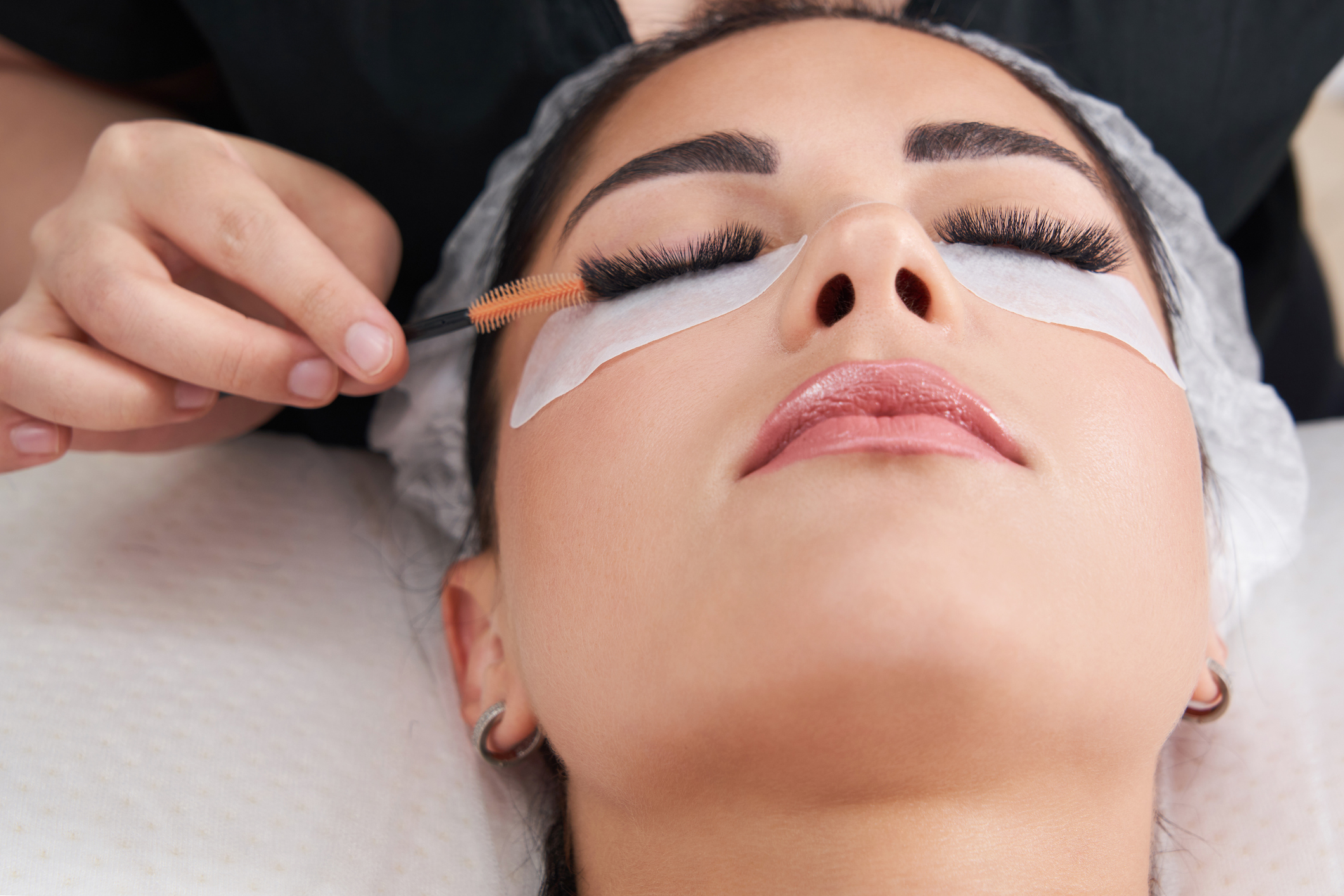 Cosmetologist making eyelash extention and correction using brush Cosmetologist making eyelash extention and correction using brush
